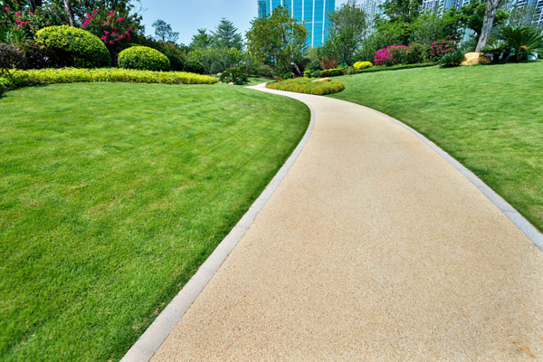 a scenic pathway winding through a lush green park with colorful flower beds and well-manicured bushes ideal for a serene nature walk