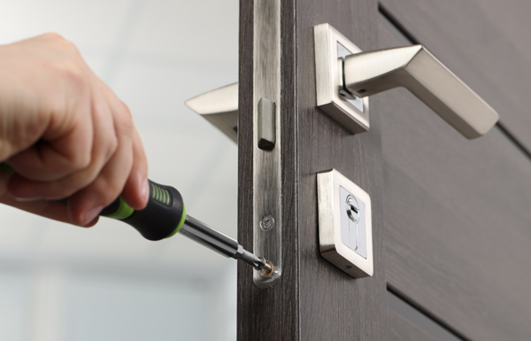 person using a screwdriver to install a door lock on a modern door