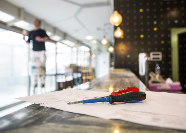 screwdriver and plans on a bar counter with a person working in background modern design interior